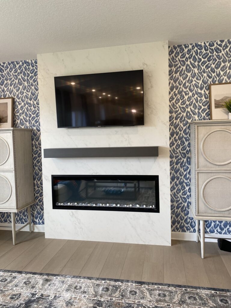 Marble look slab media wall with linear electric fireplace and floating mantel below a TV